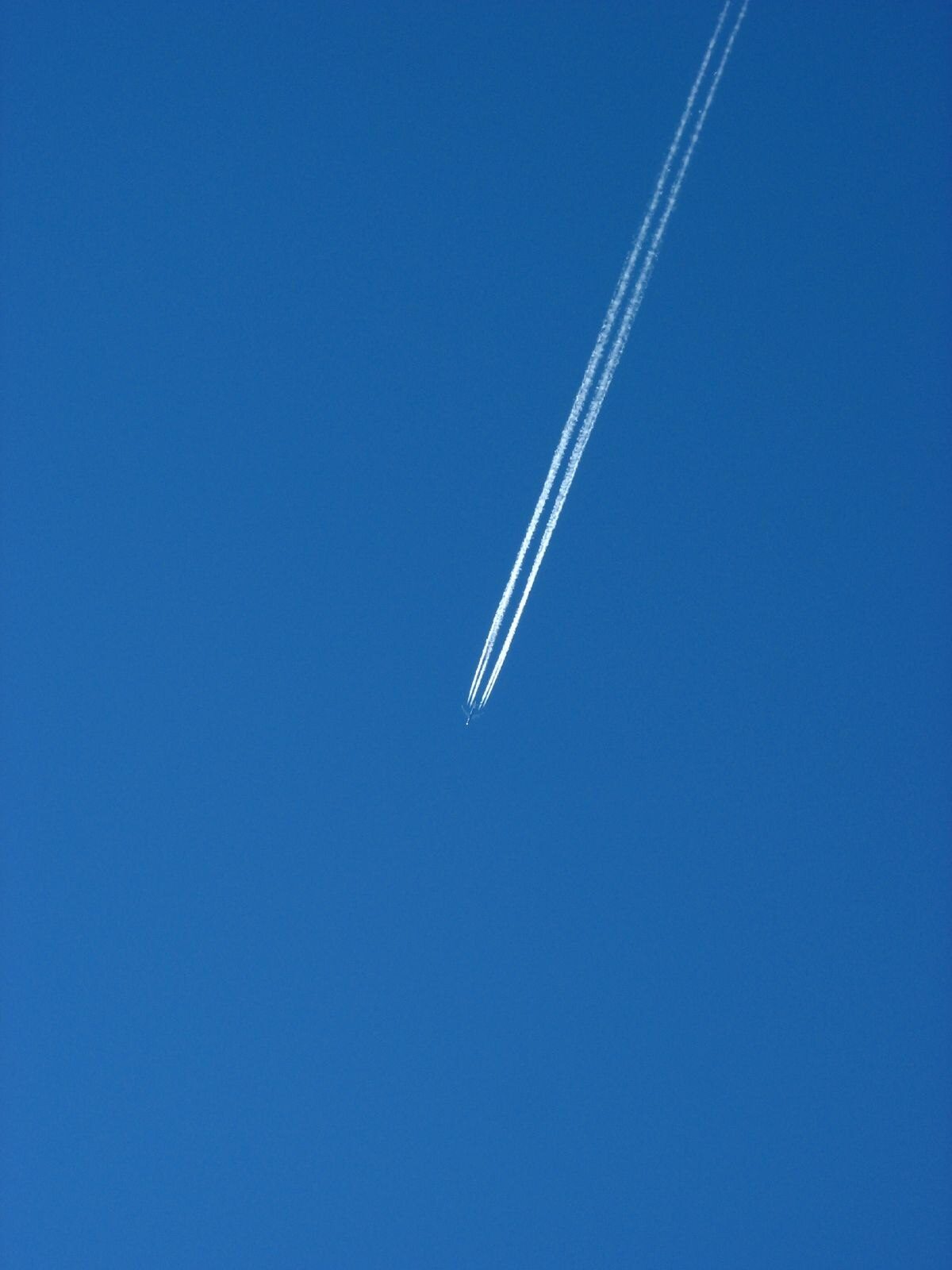 Aircraft contrail against a clear blue sky - counting contrails can help identify the number of engines